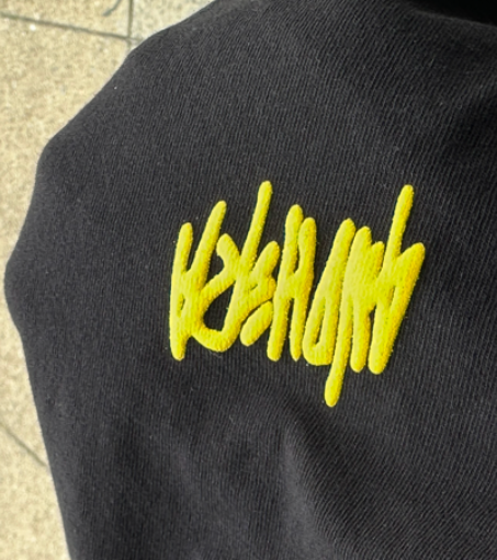 Black sweatshirt with yellow, stylized text 