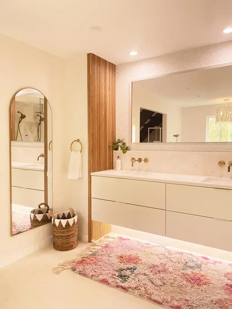 Bathroom with floating white vanity, large mirror, wooden accent wall, and colorful rug.