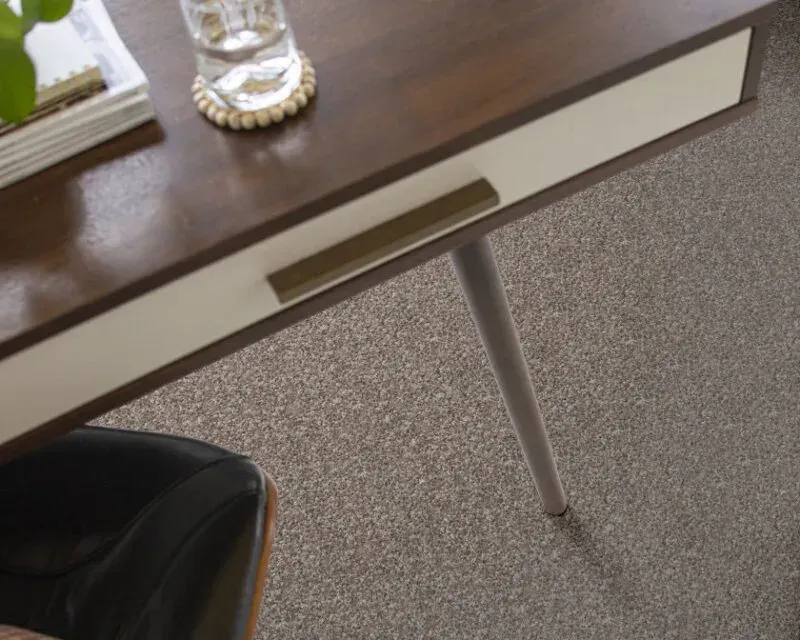Desk with drawer, glass, and dark wood top against a speckled carpet.
