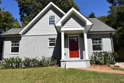 Gray brick house with red front door, white trim, and small porch.