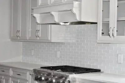 White kitchen with stove, cabinets, and backsplash.