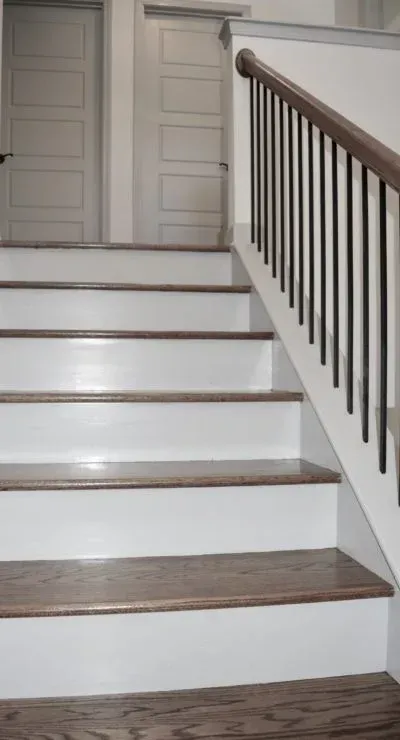 Wooden stairs with white risers and a dark railing.