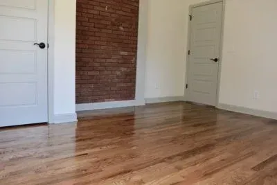 Room with hardwood floors, exposed brick wall, and two white doors.