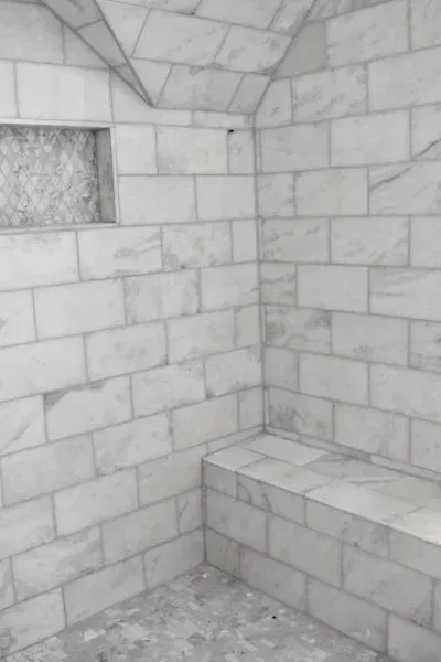 White tiled shower with built-in seat and niche.