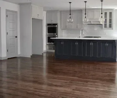 Kitchen with dark blue island, white cabinets, and wood flooring.