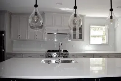 Modern kitchen with white cabinets, island, and teardrop pendant lights.