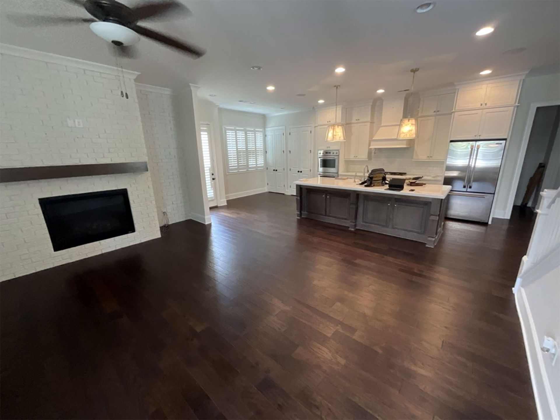 Spacious open-concept kitchen and living room with dark wood floors, fireplace, and kitchen island.