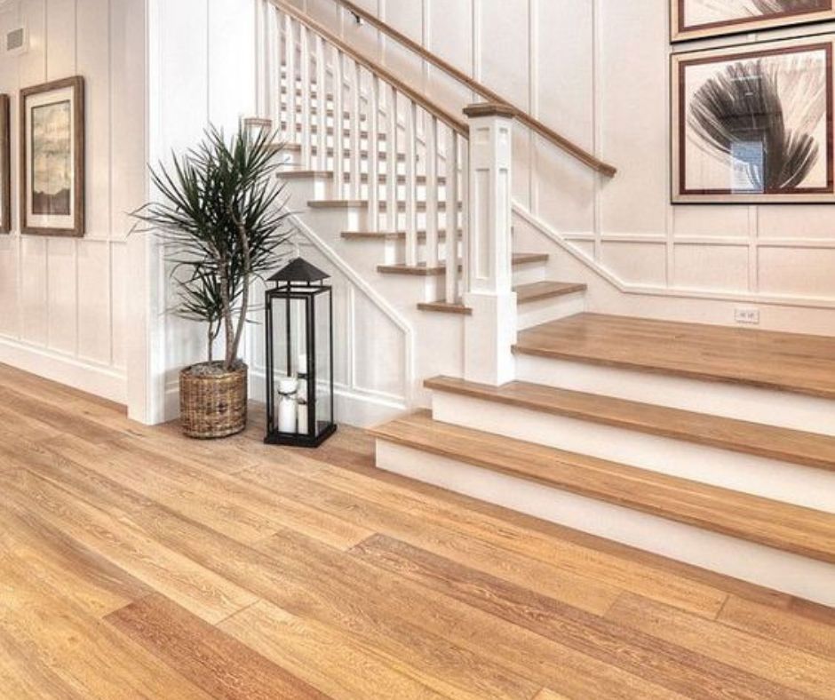 Wooden staircase with white banister and oak flooring in a well-lit home.