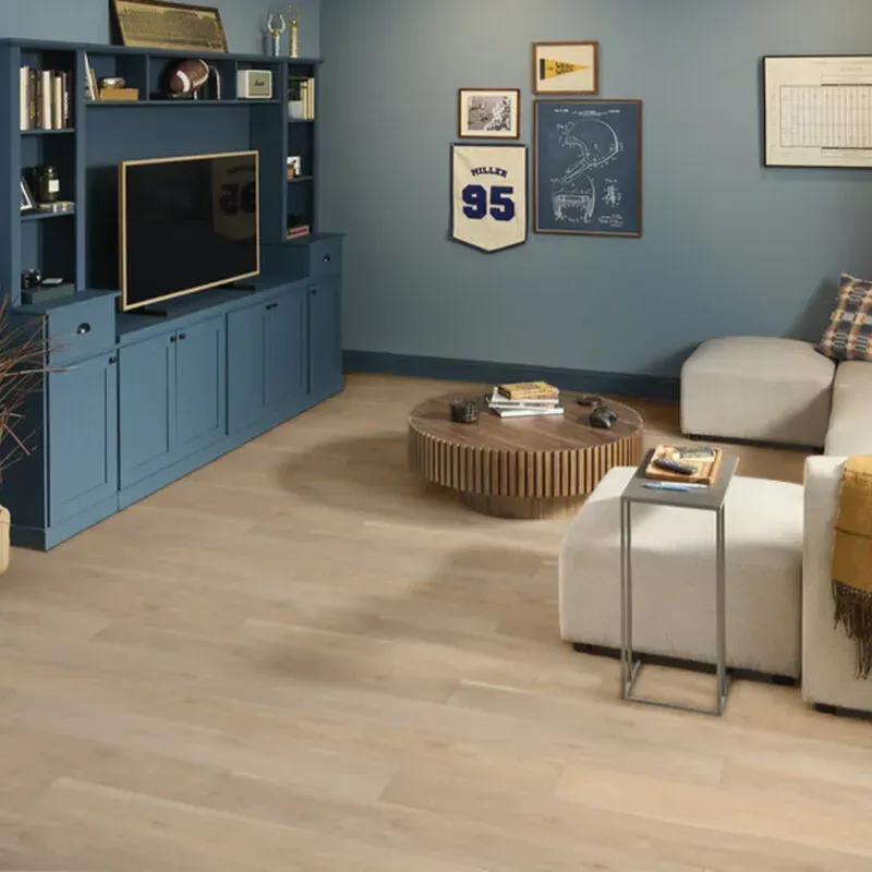 Living room with light wood floors, blue built-in cabinets, white sectional, and round coffee table.