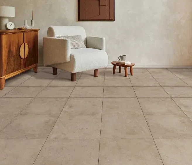 Living room with beige tiled floor, white armchair, wooden cabinet and side table.