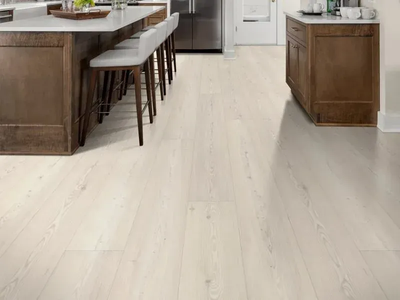 Light wood-look flooring in a kitchen with a dark wood island and cabinets.