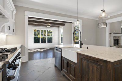 Kitchen with island, dark wood cabinets, white countertops, stove, and view into living area with fireplace.