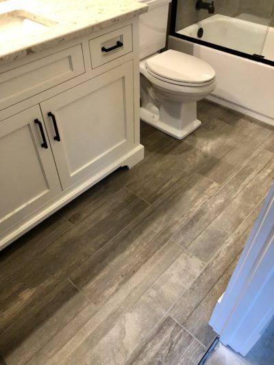 Bathroom with white vanity, toilet, and wood-look tile flooring.