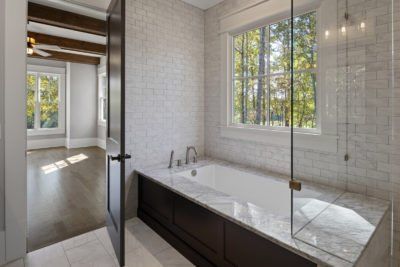 Bathroom with white tile, dark cabinetry, and a window overlooking trees.