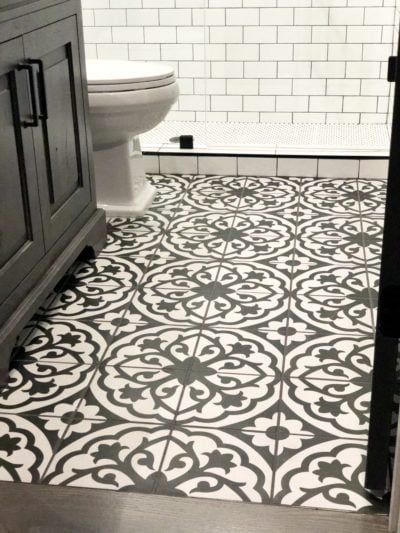 Bathroom with patterned floor tiles and white subway tile wall.