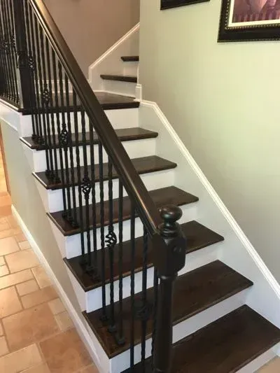 Dark wood staircase with white risers and dark metal railing in a home.