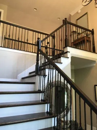 Staircase with dark wooden handrail and balusters, leading to an upper level with matching railing.