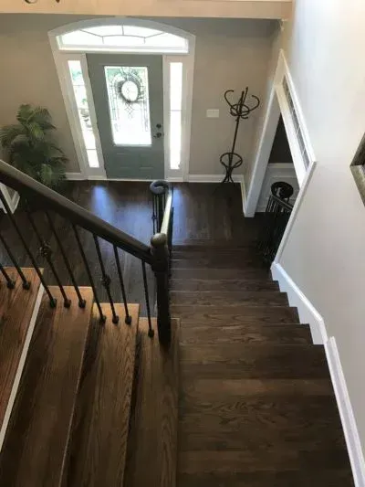Wooden staircase leading to a front door. Dark wood floors and railings, light walls.