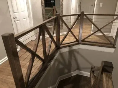 Wooden staircase railing with dark stain and wire mesh.