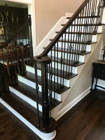 Dark wood staircase with white risers and black spindles.