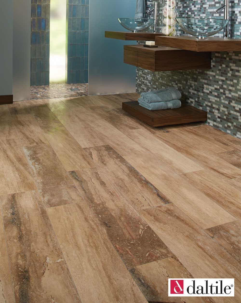 Bathroom with wood-look tile flooring. Blue and brown tiles on the wall. Glass shower door in the background.