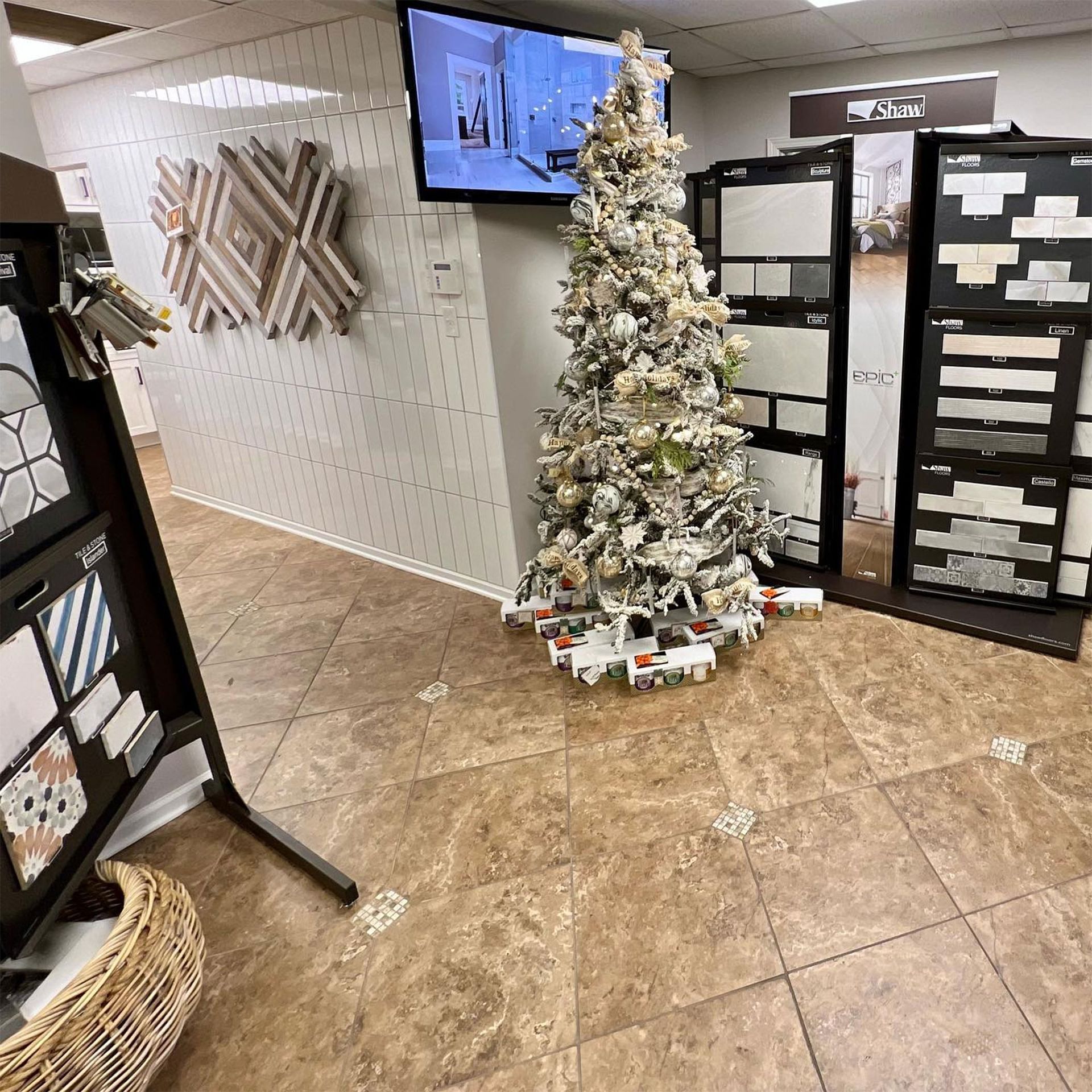 A showroom with tile displays, a decorated Christmas tree, and a TV screen.