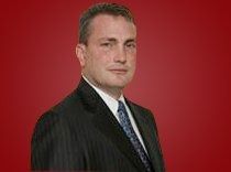 Portrait of a man in a dark suit and tie against a red background