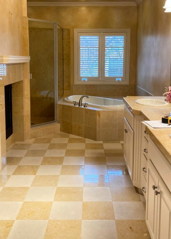Bathroom with checkered floor, tub, shower, and vanity in tan and cream tones.