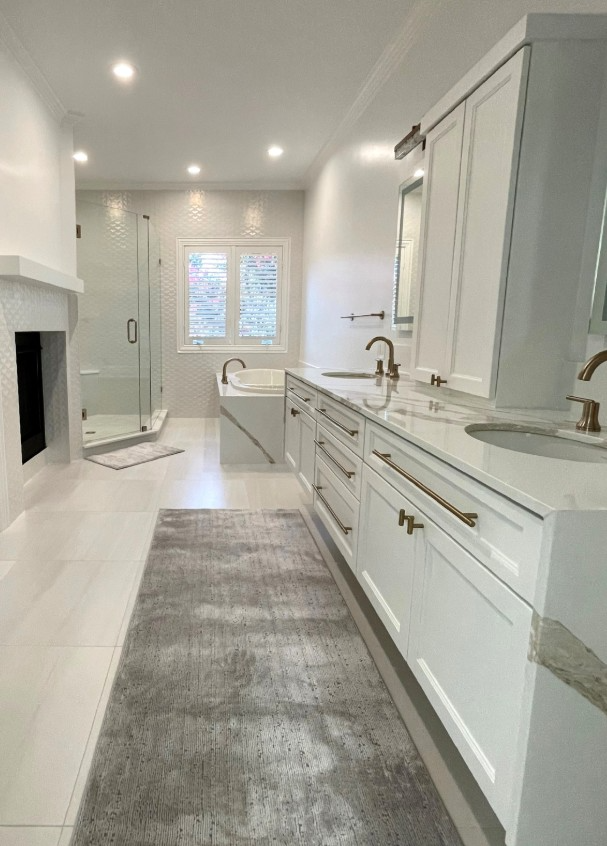 Bright white bathroom with vanity, bathtub, shower, and accent rug.