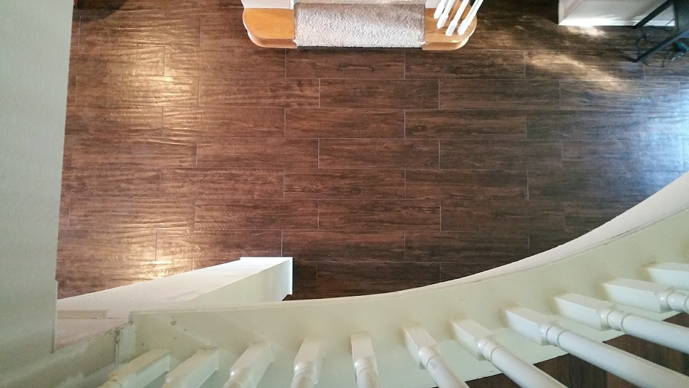 Staircase with white railing, leading down to dark wood flooring and a light-colored rug.