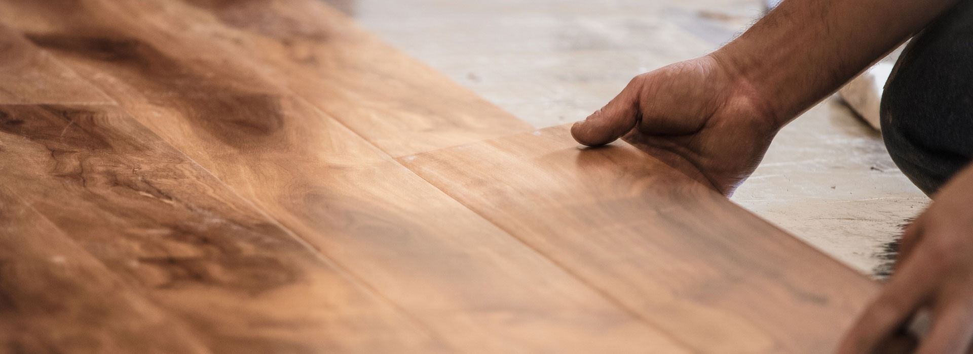 Hands placing wooden flooring planks.