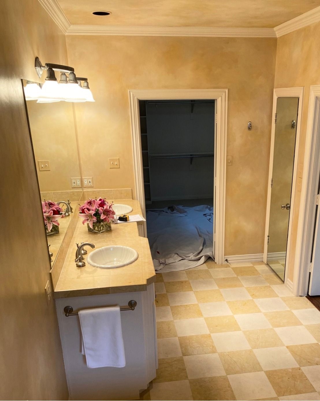 Bathroom with double vanity, checked floor, and doorway to a closet.