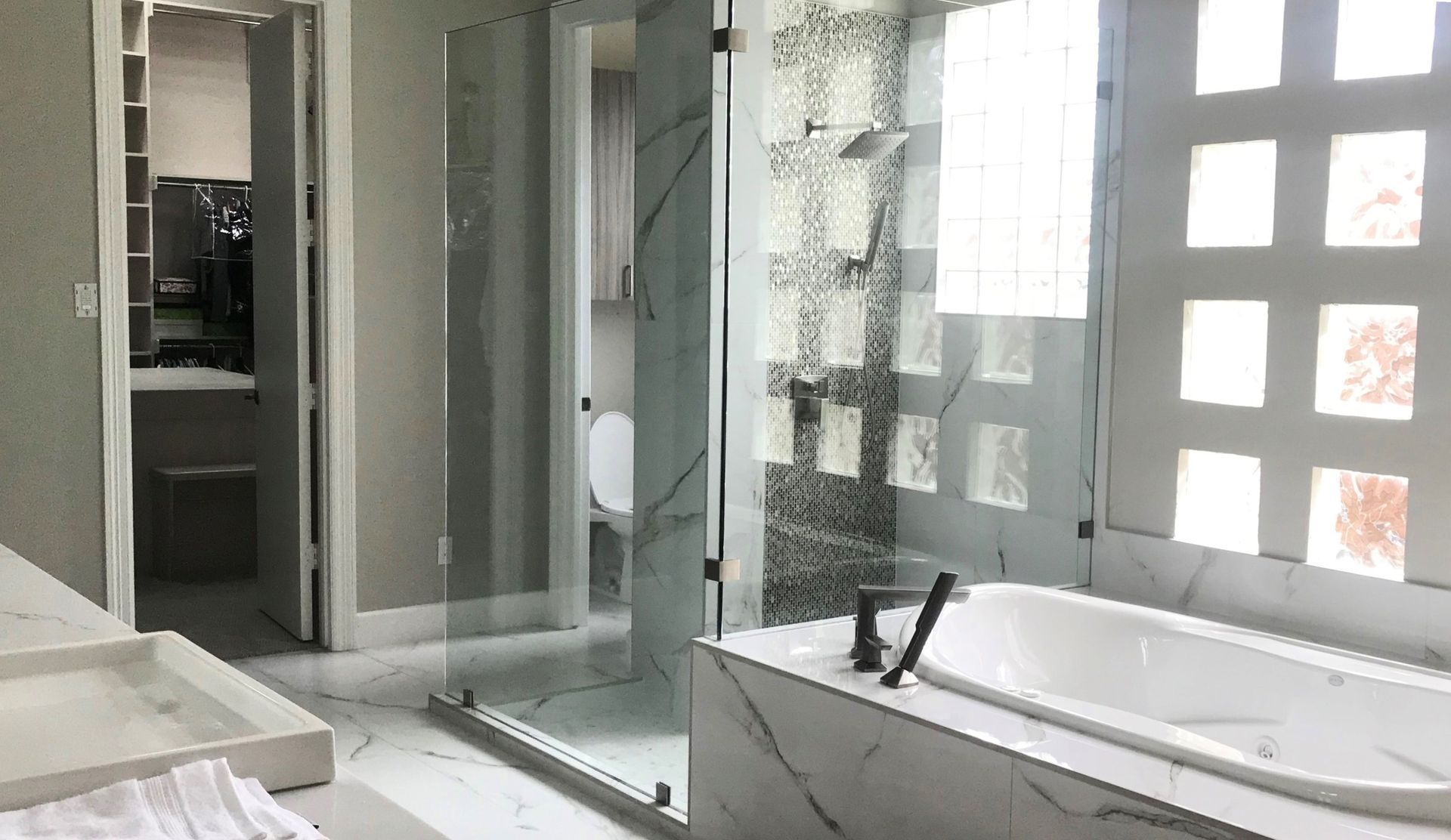 Luxurious bathroom with marble tiles, a glass shower, and a soaking tub.