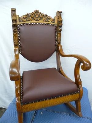 Ornate wooden armchair with brown leather seat and back, carved gold-accented frame