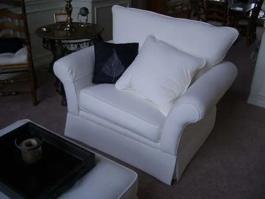 White armchair with pillows in a living room beside a dark coffee table