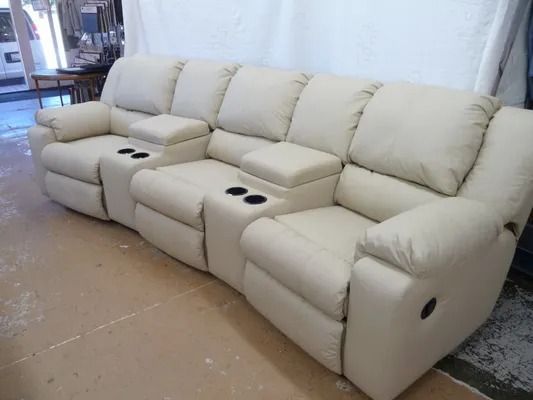 Beige leather sectional sofa with cup holders in a room