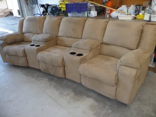 Beige reclining sectional sofa with cup holders in a garage