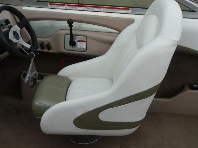 White car seat interior with a black steering wheel and dashboard controls