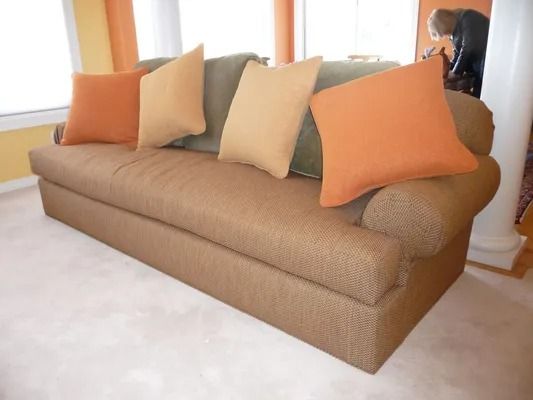 Tan sofa with orange and beige pillows in a bright living room