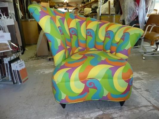 Colorful swirled armchair in a workshop or store, with bright green, yellow, orange, and blue pattern.