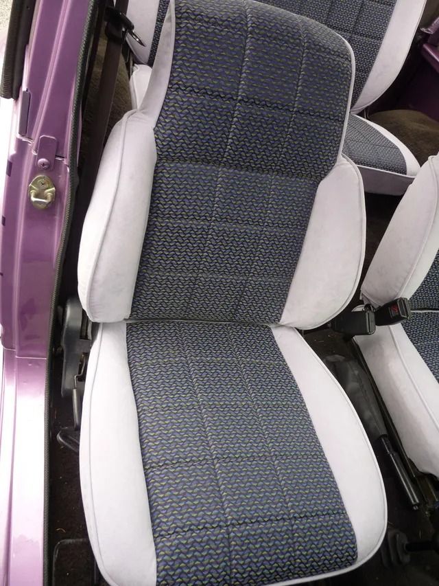 Gray and white car seat cover on a front seat, viewed from the open door