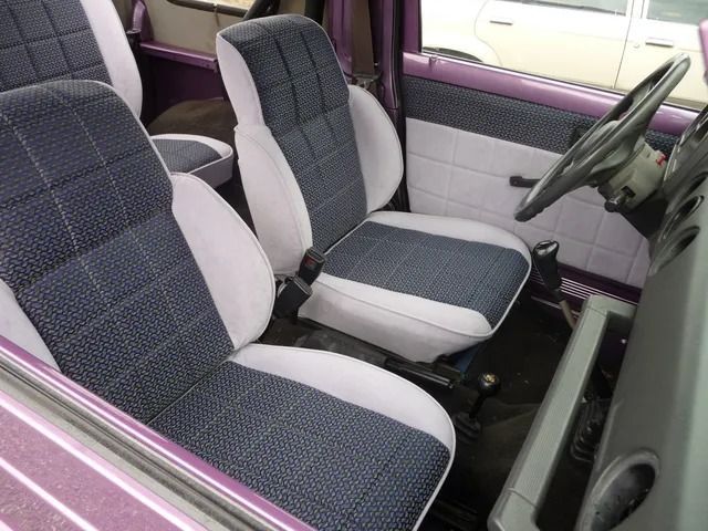 Front seats of a car with gray and blue patterned upholstery and purple door trim.