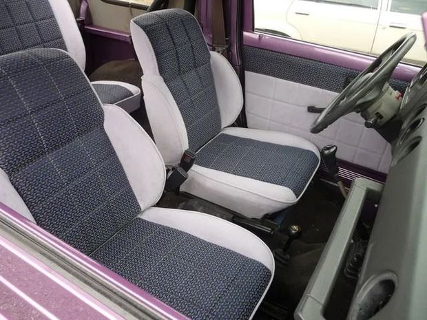 Front seats of a car with gray and blue patterned upholstery and purple door trim.
