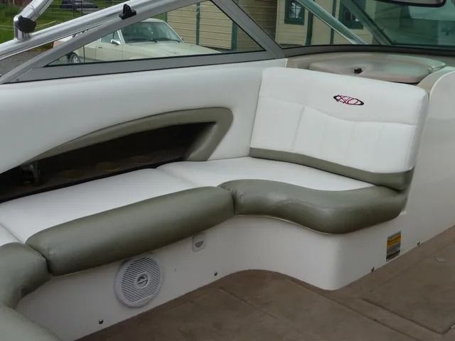 White and green padded boat bench seat with speaker and windshield visible indoors