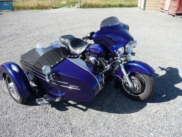 Blue custom three-wheeled motorcycle parked on pavement outdoors