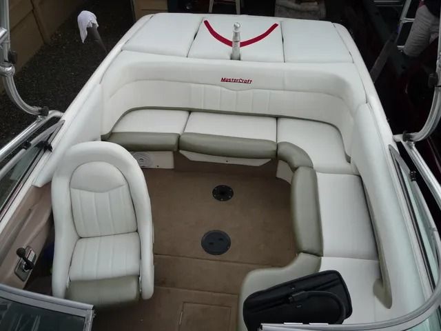 White and tan boat interior with wraparound bench seating and a central walkway on the deck