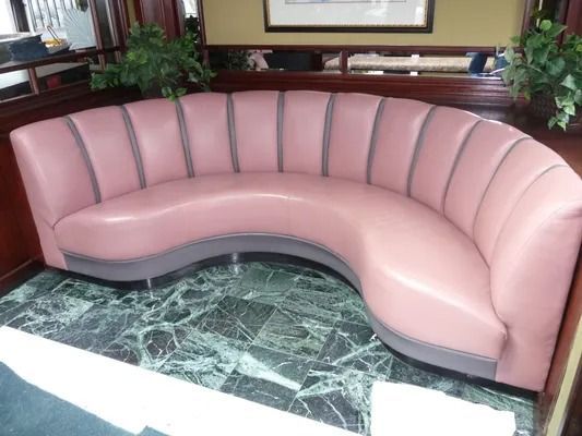 Pink curved upholstered bench in a lobby with a green marble floor