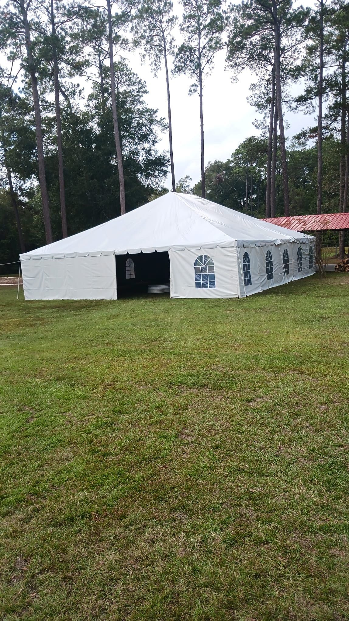 White tent set up on a grassy area with trees in the background.