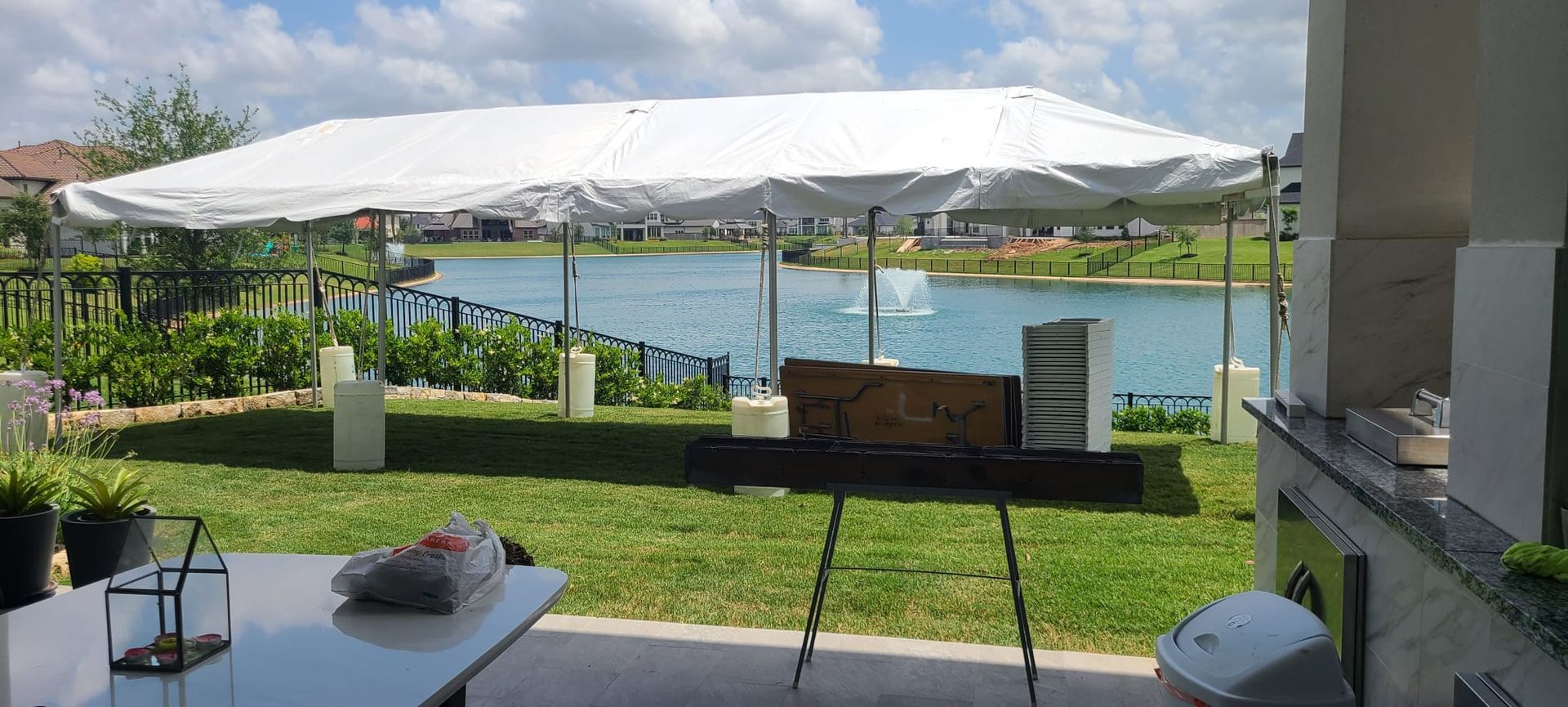 A tent set up in a backyard overlooking a lake with a fountain.