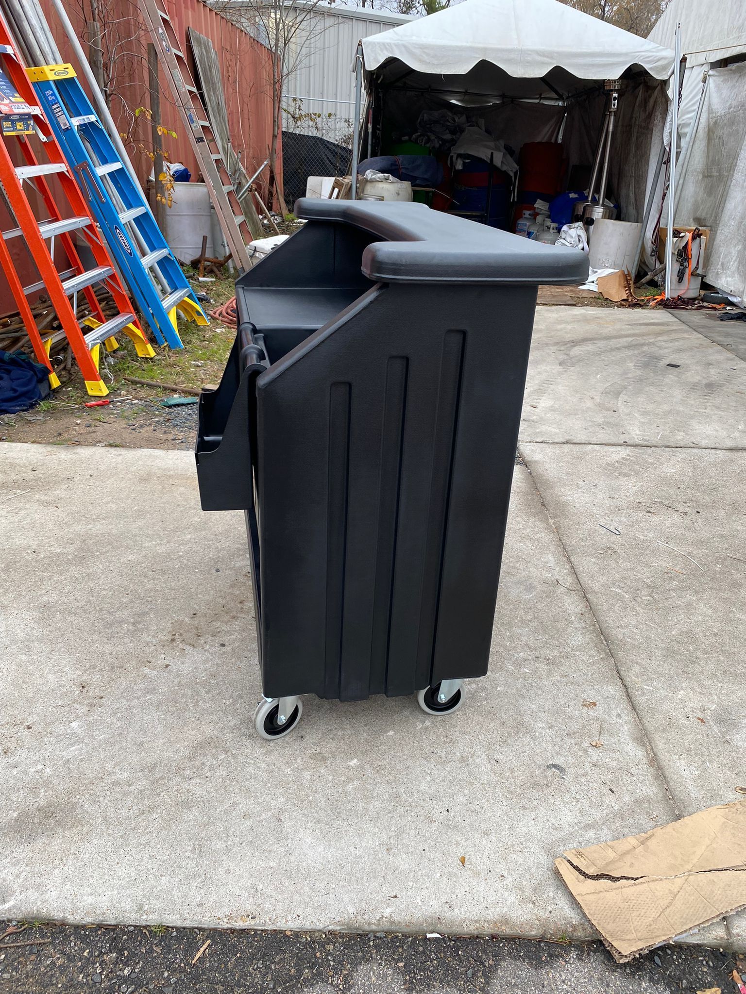 Black podium on wheels outside, a tent and ladders in the background.